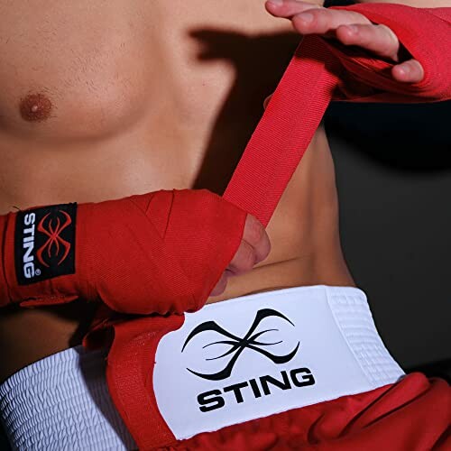 Boxer wrapping hands with red bandages.