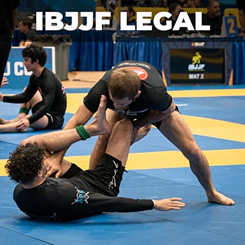 Two competitors in a Brazilian Jiu-Jitsu match on a blue mat.