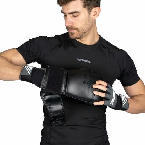 Man adjusting black boxing gloves on hands