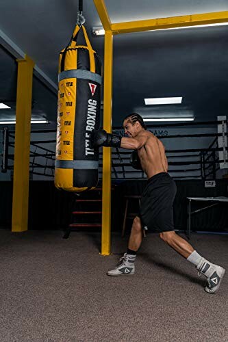 Man punching a heavy boxing bag in a gym.